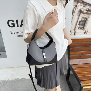 Black and grey textured dumpling bag with metal lock and adjustable strap