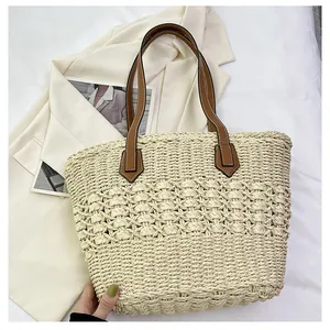 Detail of hand-woven straw tote bag with hollow diamond pattern and brown leather straps