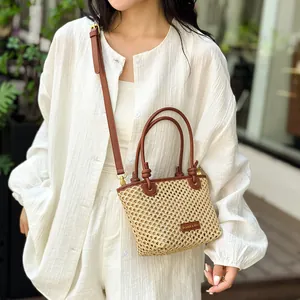 Chic straw bucket bag with brown leather trim and adjustable shoulder strap for summer