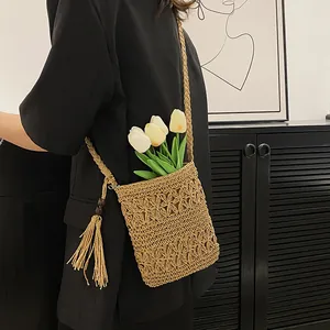 Straw crossbody bag with hollow flower patterns and tassel detail for beach vacation