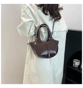 Detail einer dunkelbraunen Lackleder-Eimertasche mit glattem Halbmond-Design für Damen