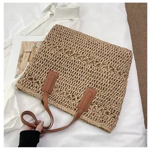 Detail of hollow-out straw weave texture and brown leather handle of a summer tote bag