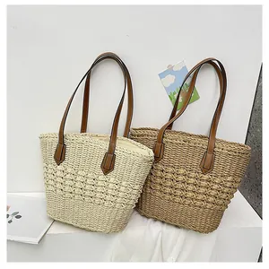 Detailed view of hand-woven hollow straw tote bags with leather shoulder straps