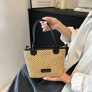 Minimalist straw bucket bag with black leather trim and knotted handle for women