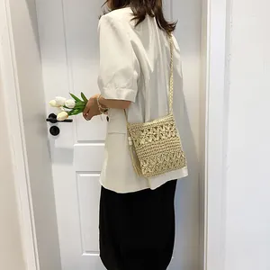 Beige hollow straw crossbody bag with floral pattern and tassel for beach vacation