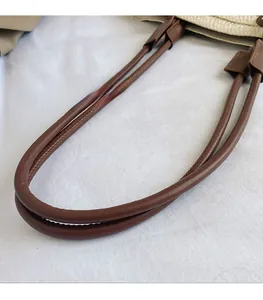 Gros plan détaillé sur la poignée en similicuir marron et la texture tissée du sac
