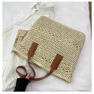 Detail of hollow woven texture and brown leather strap on a beige summer beach tote bag
