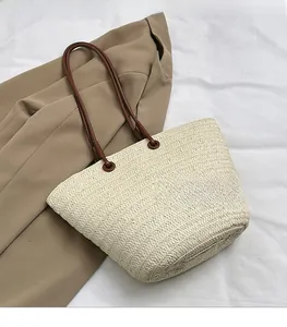 Détail de la texture d'un sac cabas tissé avec bandoulière en cuir brun et blazer kaki