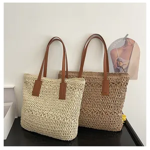 Detailed close-up of handmade hollow woven straw tote bag with premium brown leather handles