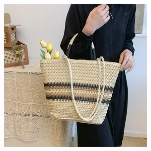 Détail d'un sac cabas en paille tissé main avec rayures noires et doubles anses