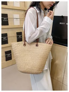 Détail de la texture tressée et de la bandoulière marron foncé d'un sac cabas en paille