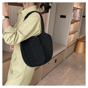 Gros plan d'un sac bandoulière noir tissé à la main montrant la texture crochetée sur le mannequin
