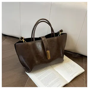 Close-up of vintage dark brown tote bag with glossy wax leather texture and gold hardware