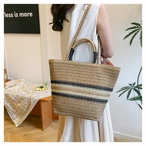 Sac cabas en paille avec rayures noires et doubles anses dans un décor minimaliste