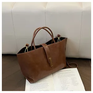 Detail view of vintage brown leather tote bag with gold metal buckle and smooth texture
