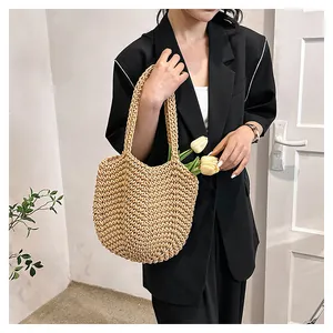 Détail d'un sac de plage en paille tissé à la main avec poignées intégrées et tulipes