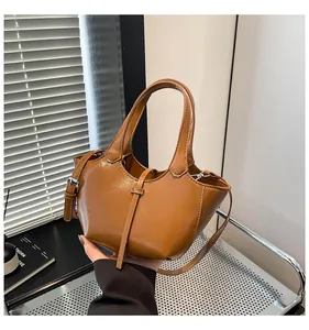 Detail einer braunen Eimertasche mit geschwungenem Design und glänzendem PU-Leder-Finish