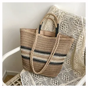 Détail du sac cabas en paille tissée avec rayures noires et doubles anses sur dentelle