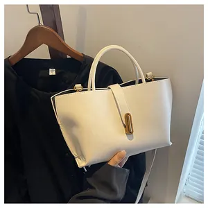 Detail of cream white leather handbag featuring a gold metal lock and fine grain texture