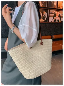 Détail du grand sac cabas tissé avec anses en cuir marron porté à l'épaule par un mannequin