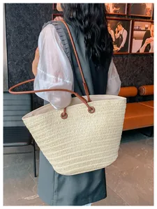 Vue lifestyle d'un grand cabas en paille tissée avec des anses en cuir marron pour le bureau