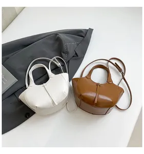 Detailansicht der perlmuttweißen und karamellfarbenen Eimertaschen mit glänzendem Finish