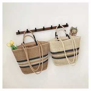 Détail du sac cabas tissé avec des rayures marron et doubles anses pour porter à l'épaule ou main