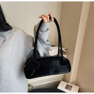 Détail du sac baguette en similicuir noir brillant avec fines anses d'épaule