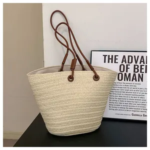 Vue détaillée du sac cabas en paille tissée beige avec élégantes bandoulières en cuir marron
