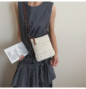Close-up of beige crochet shoulder bag featuring floral hollow pattern and brown leather strap