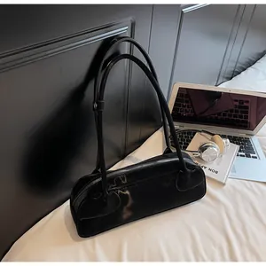 Sac baguette noir minimaliste sur drap blanc avec ordinateur et casque pour un style décontracté