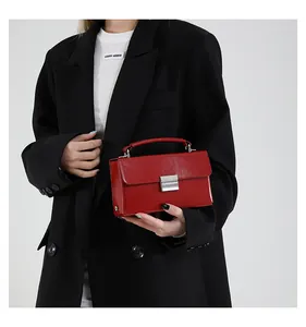 Detail der roten Lackleder-Handtasche mit silbernem Schloss und Kette auf schwarzem Blazer