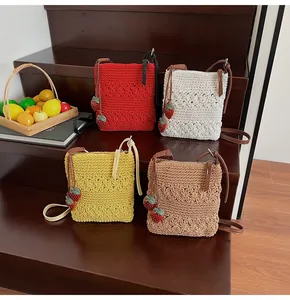 Detail of hand-woven strawberry crossbody bags in red, white, yellow and brown colors