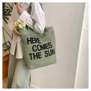 Détail du sac cabas en crochet vert avec texte Here Comes The Sun et tulipe