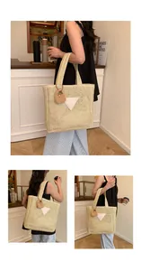 Détail d'un sac cabas en paille avec un écusson triangulaire blanc et un charme tricoté