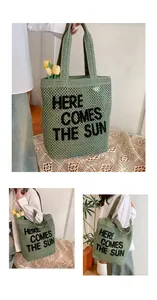 Detail of green knit tote bag with Here Comes The Sun embroidery and hollow mesh texture