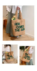 Detail of woven tote bag with 'HERE COMES THE SUN' green text and large handles
