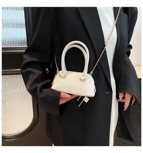 Close-up of white shell-shaped bag with lychee texture leather and gold chain strap