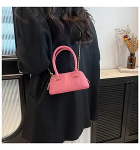 Detail of pink pebbled leather shell bag with gold chain strap on professional model