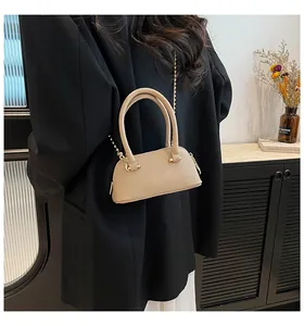 Back view of beige lychee texture crossbody bag with gold chain in a minimalist room
