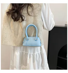Detail of light blue crossbody shell bag with gold bead chain and lychee texture
