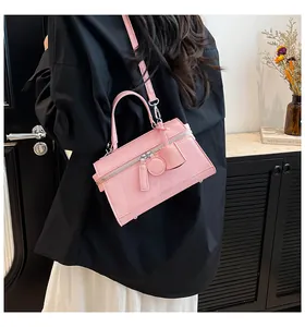 Rosafarbene Handtasche aus Leder am Modell mit verstellbarem Riemen und Metallfüßen