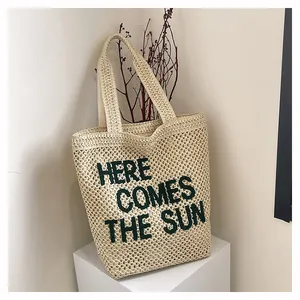 Détail de la texture tressée et de la broderie verte sur le sac cabas beige