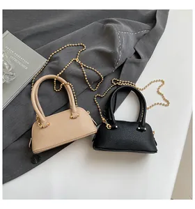 Detailed view of beige and black lychee texture crossbody bags with golden chain straps
