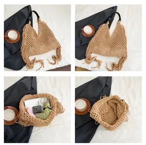 Detail view of woven straw tote bag featuring long tassels and black leather shoulder strap