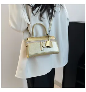 Detailansicht der goldenen Metallic-Handtasche mit Reißverschluss und Anhängern