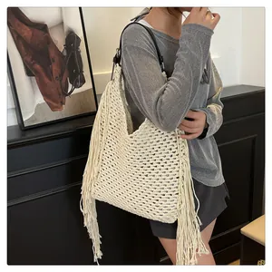 Close-up of bohemian woven tote bag with long tassels and black leather strap details