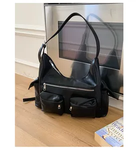 Detailaufnahme der schwarzen Kunstledertasche mit mehreren Taschen und silbernen Reißverschlüssen