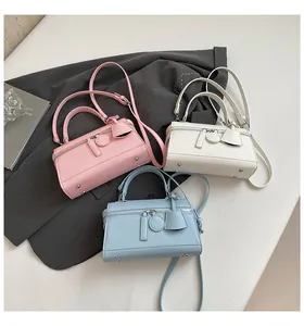 Detailansicht kleiner Box-Handtaschen in Rosa, Weiß und Himmelblau auf grauem Blazer
