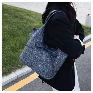 Πλάγια όψη γυναικείας τσάντας από μπλε τουίντ με διακοσμητικό φιόγκο σε εξωτερικό χώρο